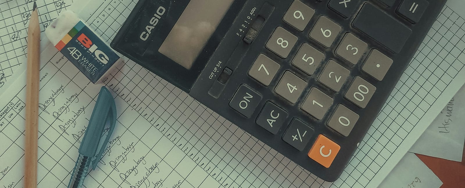 A calculator resting on a stack of paper invoices.