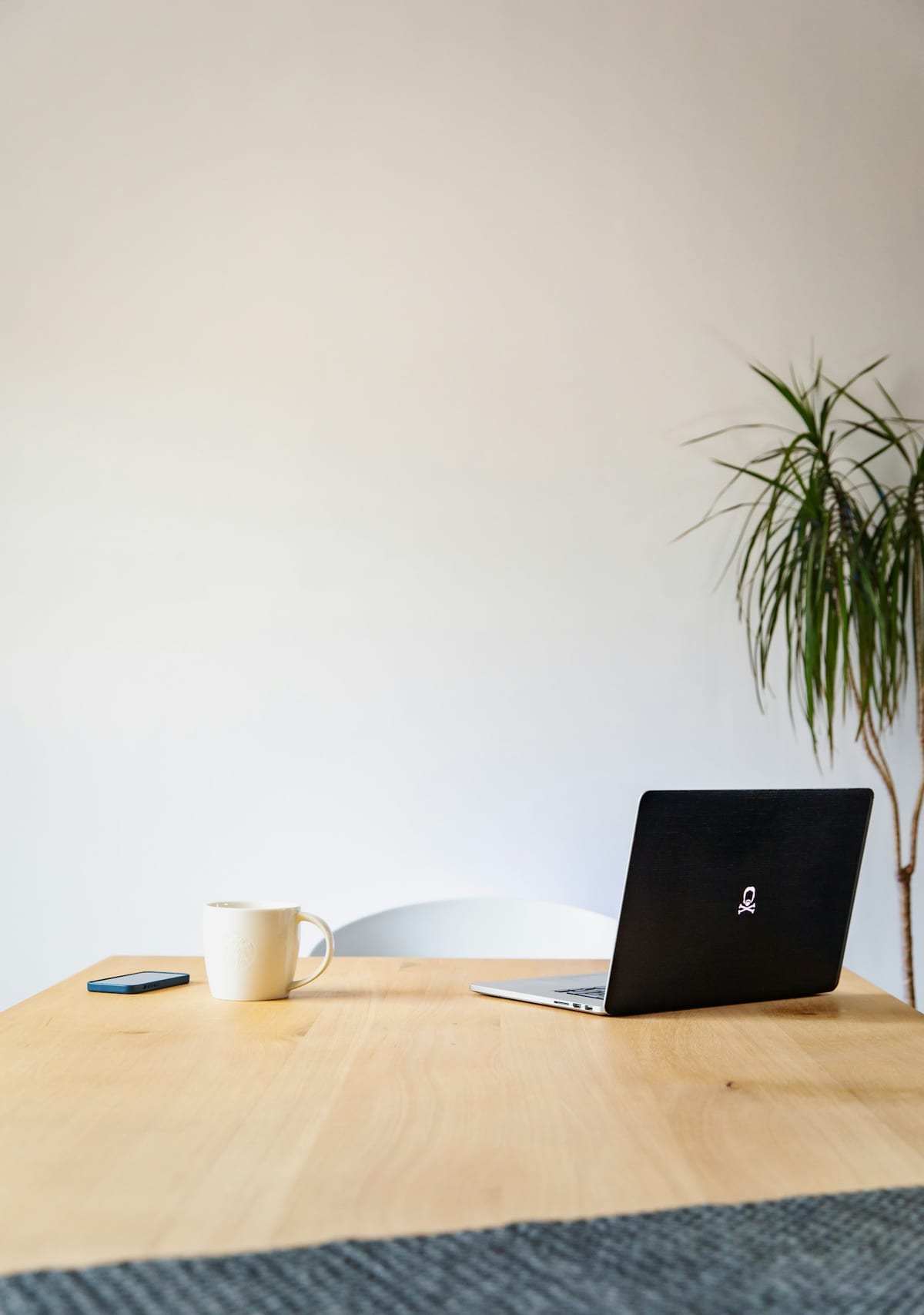 A laptop on a wooden table by a window.