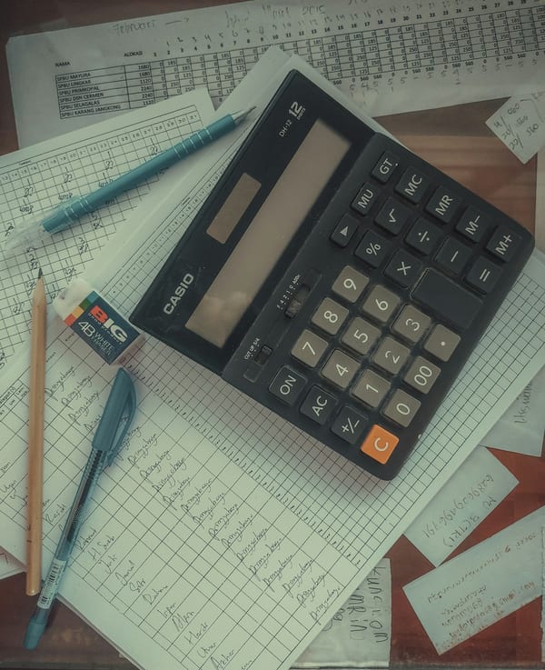 A calculator resting on a stack of paper invoices.