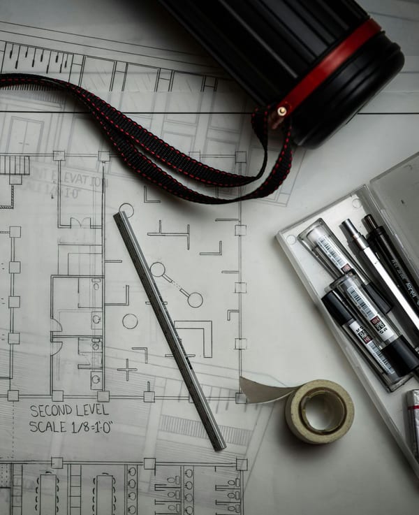 Architectural drawings on a desk with drafting pencils and a scale rule.
